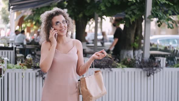 Beautiful Lady with a Bag for Souvenirs Is Talking By Phone