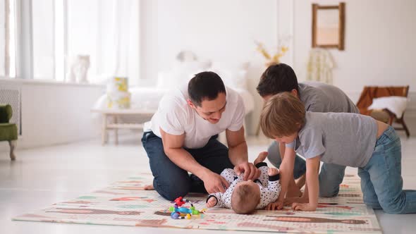 Happy Young Adult Parent Dad and Children Sons Play with Baby on Floor Carpet at Home