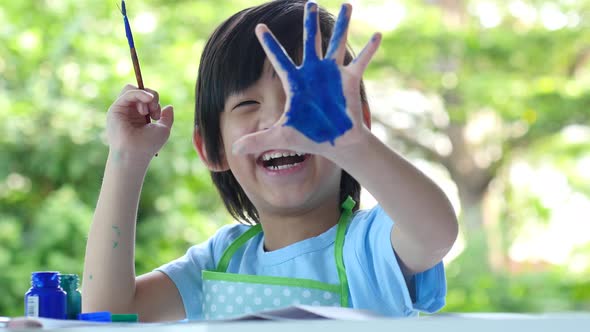 Cute Asian Child Enjoying Arts And Crafts Painting With His Hands