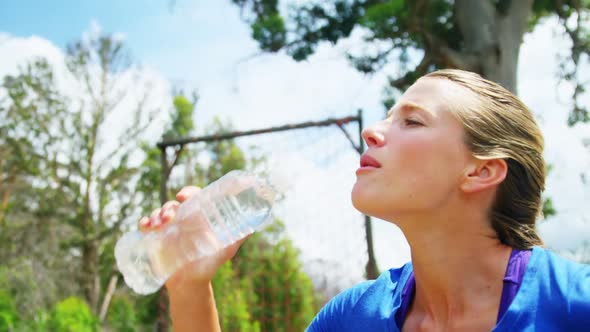 Woman drinking water from bottle during obstacle course 4k