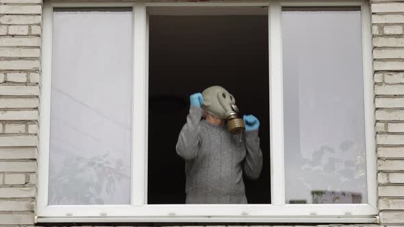 Old Man in Gas Mask Dance at Window Isolated at Home on Quarantine. Coronavirus