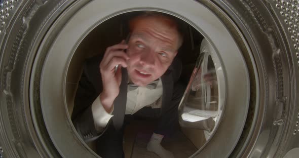 Portrait in the Washing Machine Man in a Suit Calls Repair Service Phone