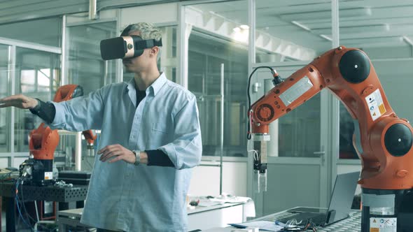 Engineer in VR-glasses Is Manipulating a Bionic Device. High School Students Studying Robotics