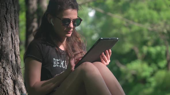 Young Woman Is Using Digital Tablet In Park