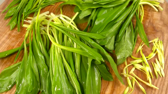 Wild garlic leaves on a wooden cutting board.