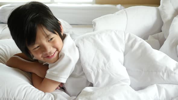 Cute Asian Child Playing Hide And Seek On White Bed