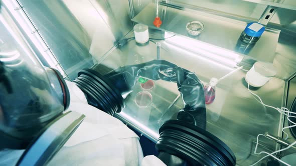 A Specialist in a Hazmat Suit is Researching Probes in a Vacuum Cabinet