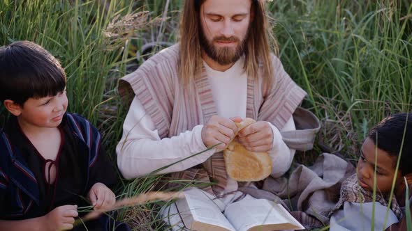 Jesus Gives Bread to Children While Sitting Among the Grass on the Hill