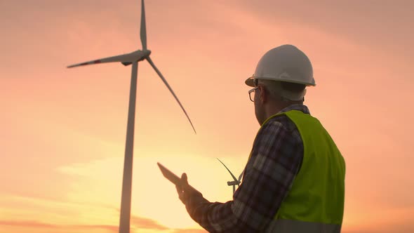 Windmill Engineer Watching Wind Turbines in Operation on a Tablet