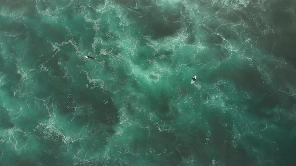 Aerial Shot of two Surfers chilling on turquoise water from above, Pichilemu, CHile-4K