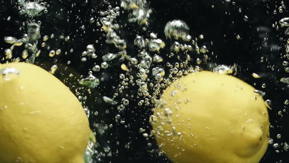 Closeup of Lemons and Limes Falling Into the Water in Slow Motion