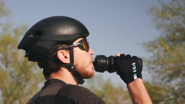 Portrait of young professional cyclist drinking water before his training session