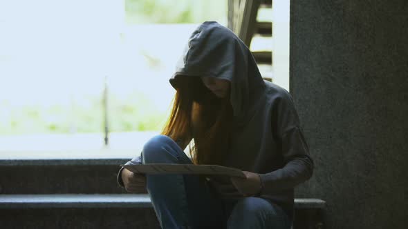 Homeless Teenage Girl in Hoodie Showing Help Sign on Stairs, Social Insecurity