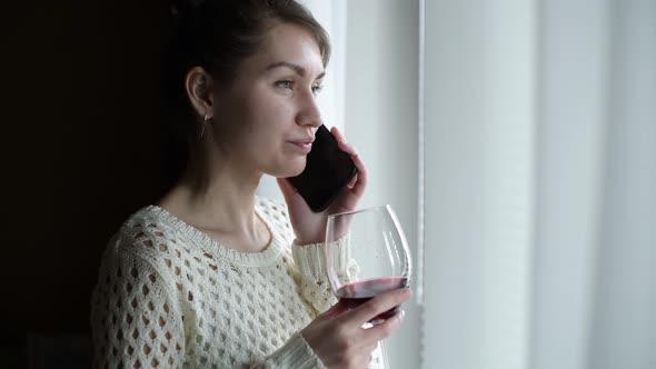 Close-up of a girl who speaks on the phone and drinks wine