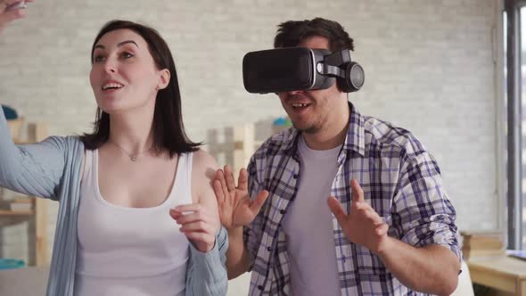 Young Woman Shoots the Reaction of a Man in Virtual Reality Glasses on the Phone