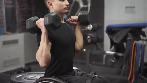 Workout Young Disabled Athlete in Wheelchair Performs Exercises with Dumbbells Gym Training and