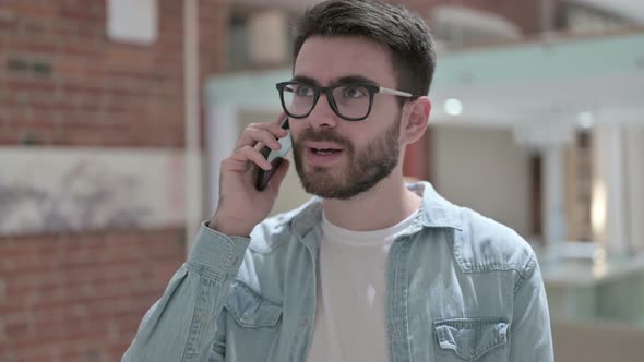 Portrait of Young Male Designer Talking on Smartphone