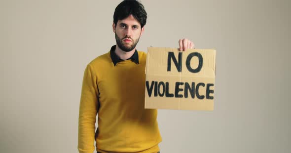 Young Boy in a Yellow Shirt Raises a Protest Sign That Says No Violence