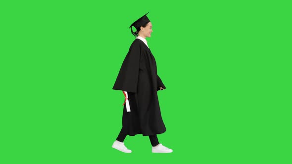 Smiling Female Student in Graduation Robe Walking with Her Diploma on a Green Screen Chroma Key