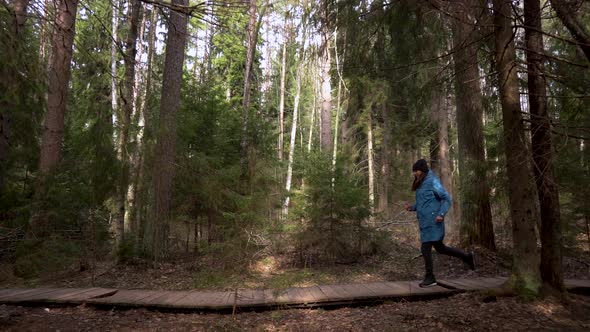 Woman in a Blue Raincoat Makes A Run On The Forest Road