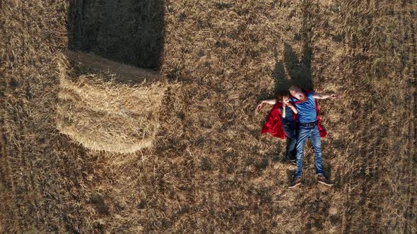 Top View of Dad and Son Superheroes Lying on Field