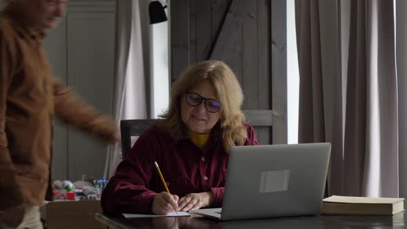 two elderly people surfing internet on laptop computer at home.