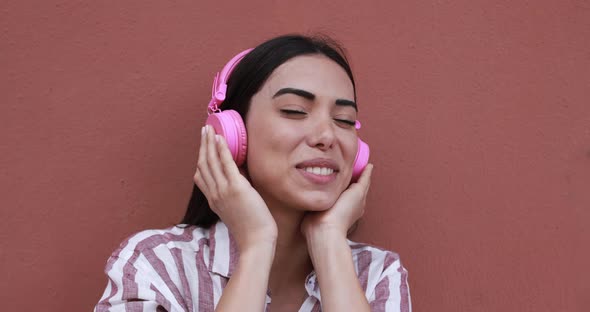 Young latin woman wearing headphones while listening music playlist