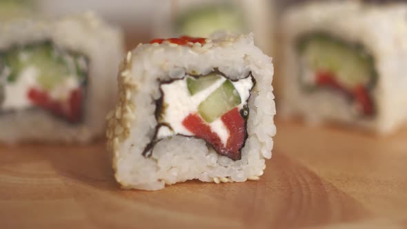 Japanese Cuisine Piece of Sushi Roll with Cheese Cucumber and Salmon in Sesame Sauce is Poured