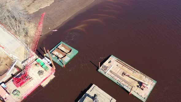 An aerial shot over a construction site in a creek. The drone camera tilt down & truck right orbitin