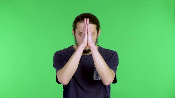 A Darkhaired Young Man in a Black Tshirt Holds His Palms Together in a Prayer Gesture