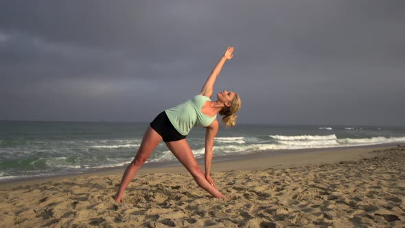 A young attractive woman doing yoga on the beach.