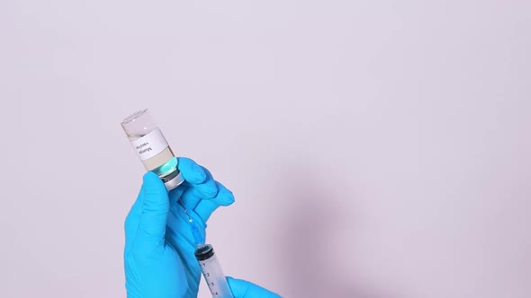 A Doctor Holds a Mumps Vaccine and Picks the Drug Up in a Syringe on a White Background
