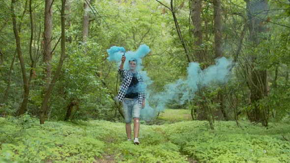 Young Man with Smoke Bomb Walking in Forest