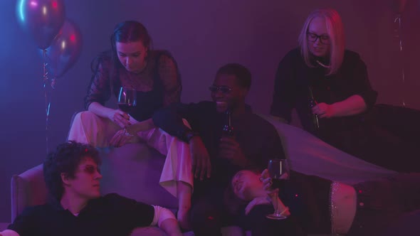 Friends Chatting and Drinking at Neon Party