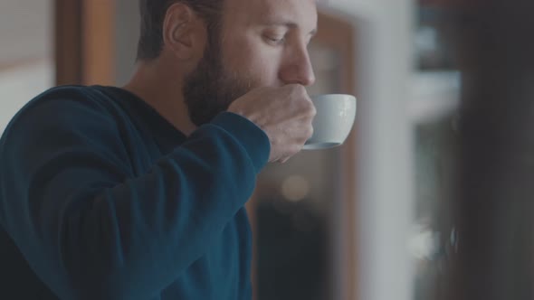 Relaxed Caucasian Man with Beard Drinks Coffee in a Cafe