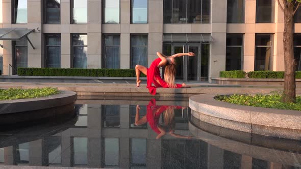 Beautiful Young Girl Dancing on the Street of a Modern City and Is Reflected in the Water. She Is