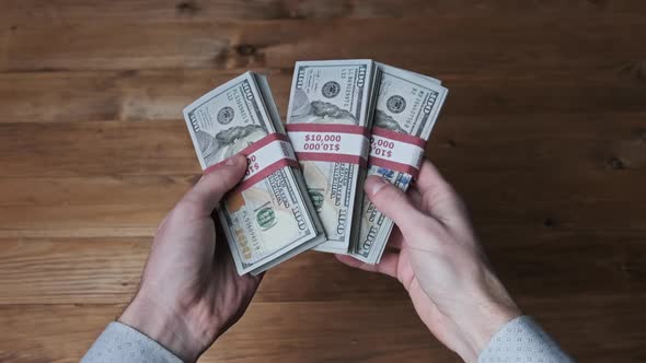 Male Hands Hold Three Stacks of 10000 US Dollar Bills and Show Thumb Up Sign