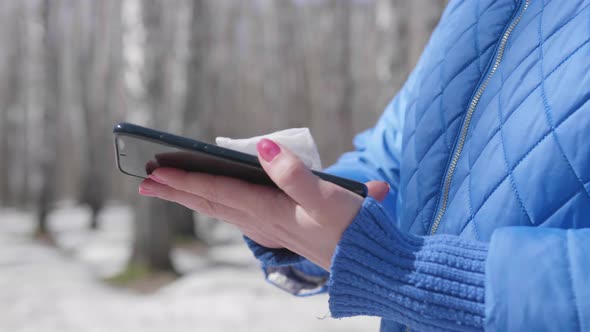 The Girl Wipes Her Mobile Phone with a Antibacterial Wipe on the Street. Prevention and Protection