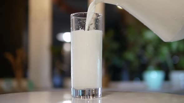 Pouring Natural Milk From A Jug Into A Glass On A Turntable, Fresh Dairy Product In A Glass