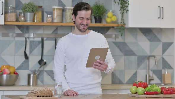 Young Man Doing Video Call On Tablet in Kitchen