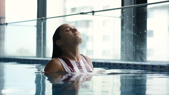 Closeup of Young Woman Enjoying and Relaxing in Indoor Swimming Pool