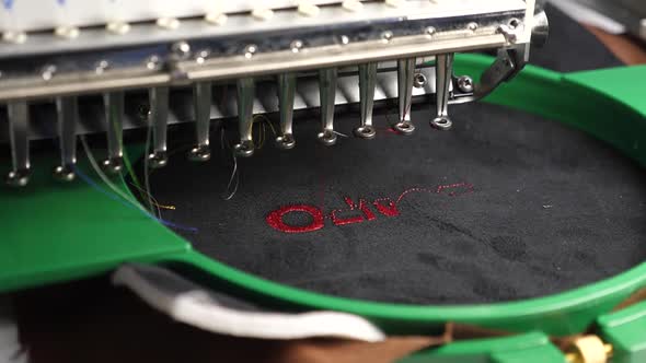 an Automated Machine Embroiders Pattern with Red Threads on a Black Cloth. Robotics Works in