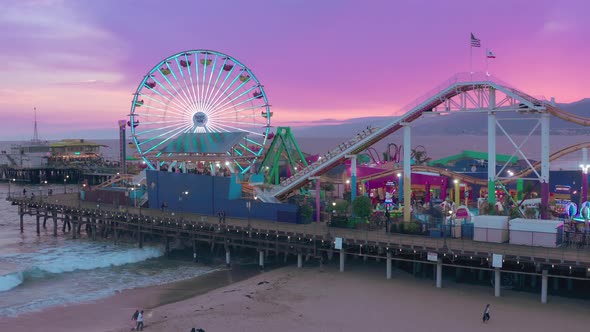 The Aerial View Over the Santa Monica Pier,glowing Ferris Wheel,rides and Cityscape Behind the Shore alt