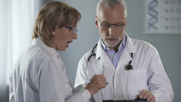 Doctors Having Discussion on Results, Woman Holding Tablet, Man With Notepad