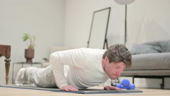 Tired Middle Aged Man Doing Pushups on Yoga Mat at Home