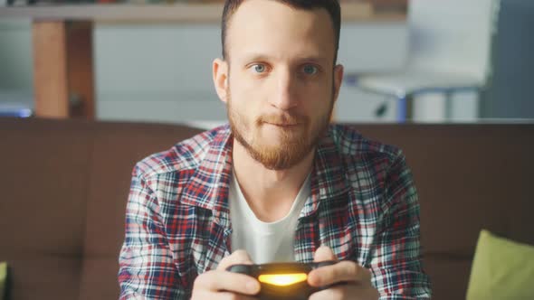 A Excited Young Gamer Is Sitting on a Couch and Playing Video Games on a Console