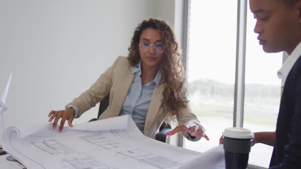 Biracial female architects talking and checking architects plans in modern office