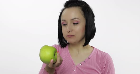 Young Beautiful Woman Eating Big, and Juicy Green Apple on White Background