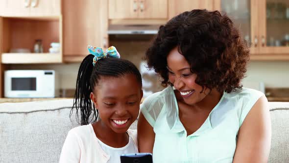 Mother and daughter using mobile phone in living room 4k