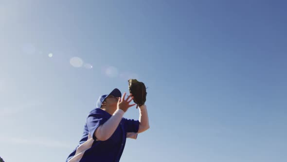 Mixed race female baseball fielder catching and dropping ball on sunny baseball field